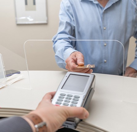 A man using a credit card to pay the cost of dental care