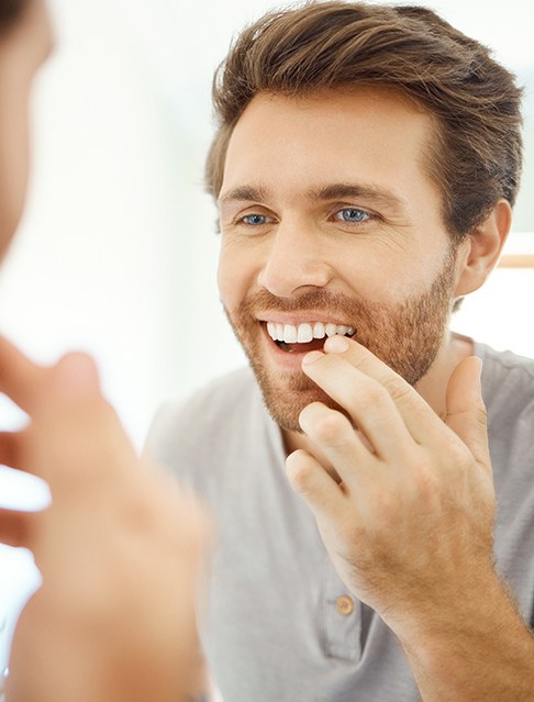 Patient in Castle Rock smiling in mirror after cosmetic dental bonding