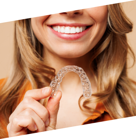 Smiling woman holding a clear aligner