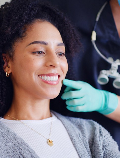 A smiling woman in a dentist’s office admiring her treated smile