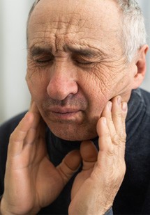 Patient in Parker holding cheeks due to dental pain