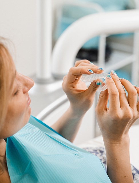 Patient holding a clear aligner in treatment room