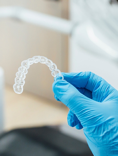 Dentist with blue gloves holding clear aligner