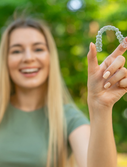 Teen girl smiling while holding clear aligner