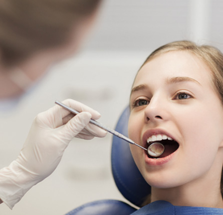 Dentist looking at teen's teeth in treatment room