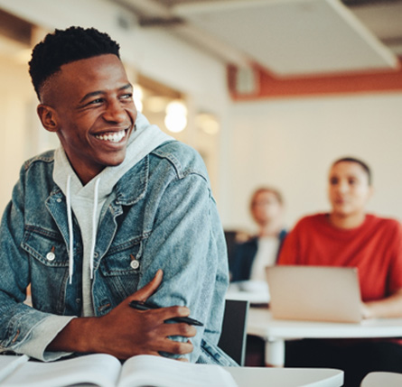 Teen in jean jacket smiling in classroom