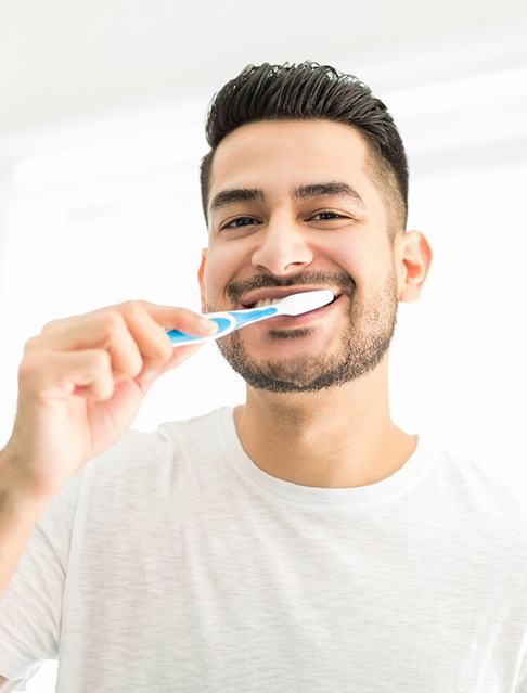 Man smiling while brushing teeth