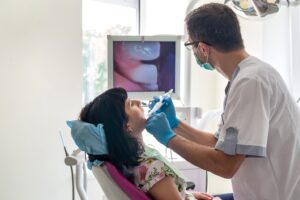 Dentist working on patient with intraoral camera and looking at screen.